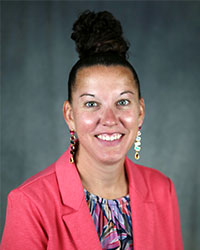 Woman smiling wearing pink jacket and colorful top